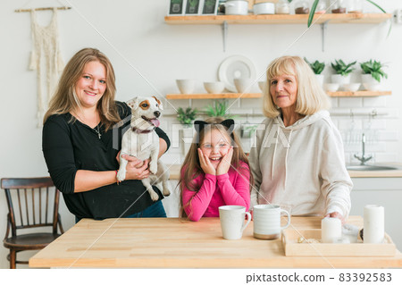 Happy granddaughter and grandmother and daughter having fun with jack russell terrier dog. Grandma hugs grandchild at home. Relationship, family and three generation concept. Happy granddaughter and grandmother and daughter having fun with jack russell terrier dog. Grandma hugs grandchild at home. Relationship, family and three generation concept. 83392583