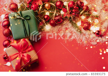 Festive boxes on a red background with Christmas toys balls a branch of fluffy fir tree, sparkles with confetti lights. New Year Christmas concept. Flat festive mockup with copy space 83393173