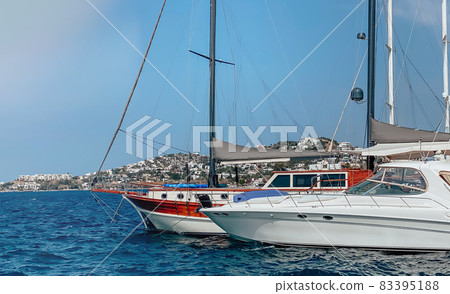 View of the embankment of a resort town in Turkey with boats moored at the pier overlooking the mountains and the sea 83395188