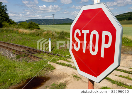 A red STOP sign before crossing the tracks. A red STOP sign before crossing the tracks. 83396050