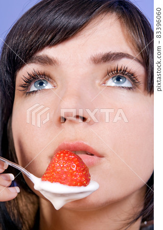 The portrait of woman with strawberry with yogurt on a spoon 83396060