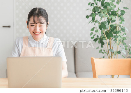 A woman in an apron using a computer (smile) 83396143