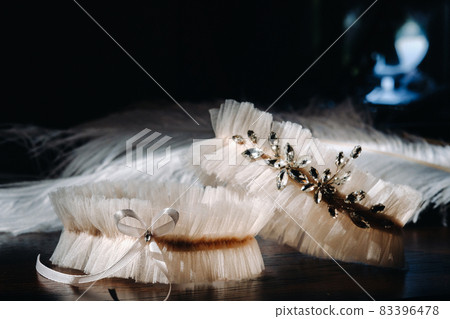 Two white garters of the bride are lying on the table 83396478