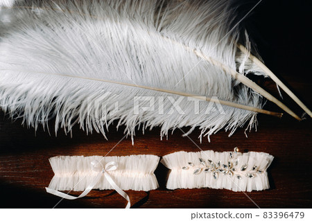Two white garters of the bride are lying on the table 83396479