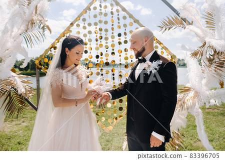 happy wedding couple near the arch wearing rings during the wedding ceremony 83396705