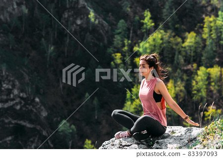 An attractive and healthy young woman does yoga in the mountains at dawn. Yoga in the fresh air. Happy woman doing yoga exercises. Meditation in nature. A woman practicing yoga in the mountains An attractive and healthy young woman does yoga in the mountains at dawn. Yoga in the fresh air. Happy woman doing yoga exercises. Meditation in nature. A woman practicing yoga in the mountains 83397093