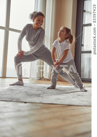 Jolly woman enjoying home workout with daughter 83397419