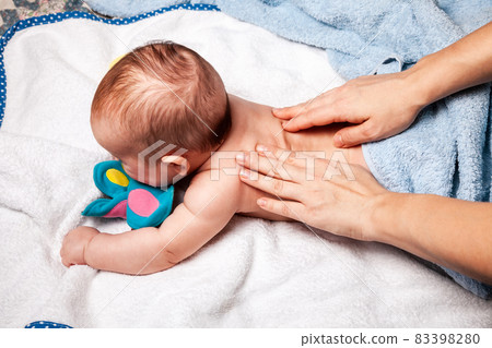 Little baby receiving chiropractic treatment of her back at home 83398280