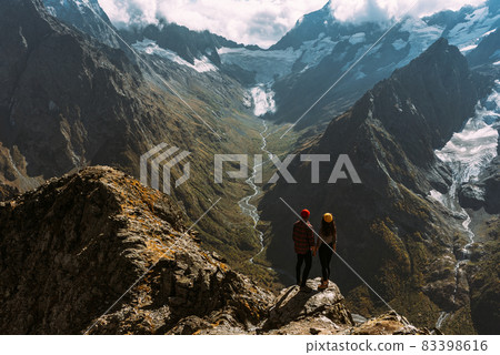 The couple travels through the Caucasus mountains. Man and woman traveling. A walk in the mountains. The couple greets the sunrise in the mountains, rear view. A man and a woman in the mountains The couple travels through the Caucasus mountains. Man and woman traveling. A walk in the mountains. The couple greets the sunrise in the mountains, rear view. A man and a woman in the mountains 83398616