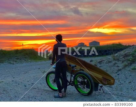 Surfer watching the sunset Surfer watching the sunset 83399100