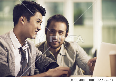 two young asian entrepreneurs discussing business using laptop computer in office two young asian entrepreneurs discussing business using laptop computer in office 83399273