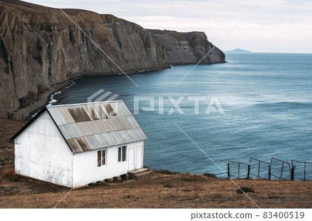 White house on the beach. A lonely house on a promontory by the sea. Seascape. An old abandoned house by the sea. Copy space 83400519