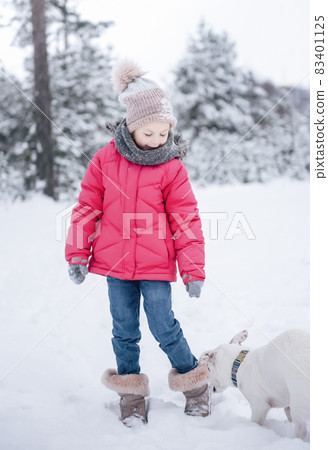 Little girl in a bright jacket plays in the winter snowy forest with her dog Little girl in a bright jacket plays in the winter snowy forest with her dog 83401125