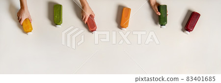 Flat-lay of human hands holding fresh juices in Flat-lay of human hands holding fresh juices in 83401685