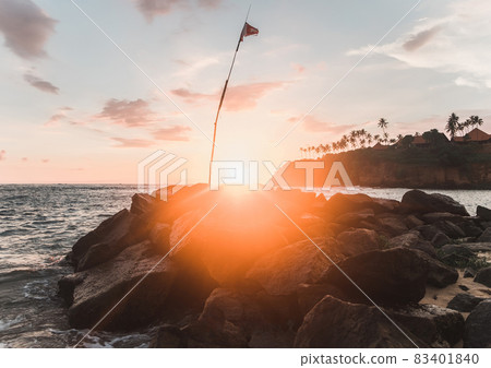 Bright ray of sunlight on a rocky beach by the sea. Vibrant ray of light at sunset.  83401840