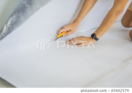 man and a roll of insulating cloth to install a laminate wooden floor 83402574