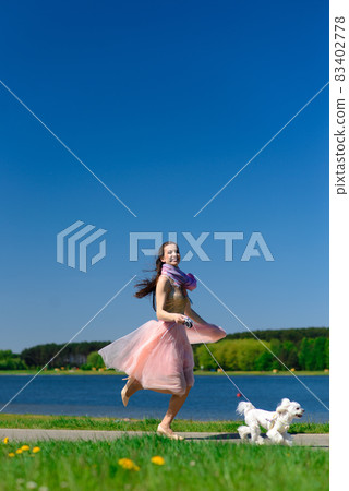 Puppy white dog with it's owner. Concept about friendship, animal and freedom. Puppy white dog with it's owner. Concept about friendship, animal and freedom. 83402778