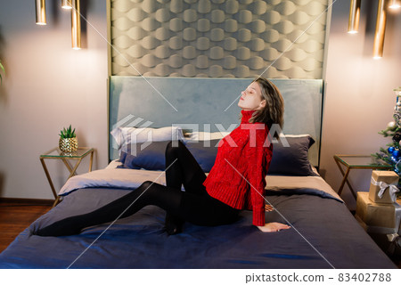 Happy emotional surprised young woman by Christmas tree in cozy living room, concept of happiness 83402788