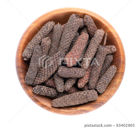 Long pepper in wooden bowl, isolated on white background. Heap of pippali or piper longum. Top view. Long pepper in wooden bowl, isolated on white background. Heap of pippali or piper longum. Top view. 83402905