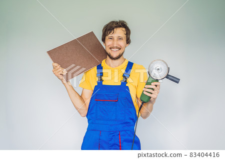 A tiler, a tiling specialist, holds a tile cutter in his hands A tiler, a tiling specialist, holds a tile cutter in his hands 83404416