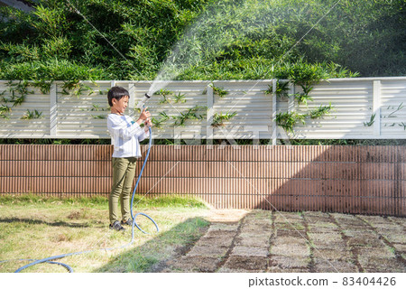 Elementary school boy watering the lawn 83404426