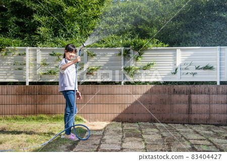 Elementary school girl watering the lawn 83404427