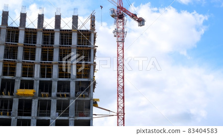 construction crane and unfinished residential buildings against the backdrop of blue sky and 83404583