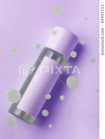 Drops of cosmetic makeup remover over the bottle on a purple background 83405513