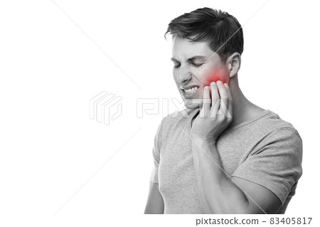 Sad young european male suffering from toothache, presses hand to cheek with painful expression, monochrome photo Sad young european male suffering from toothache, presses hand to cheek with painful expression, monochrome photo 83405817