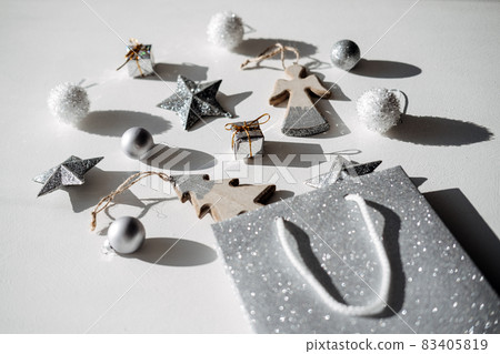 Christmas sale, shopping. Modern pattern, minimal flatlay with silver glitter star and wooden toys. Christmas white silver background with shopping bag and xmas ornaments. 83405819