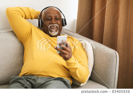 Senior African American Man Listening Music On Smartphone At Home Senior African American Man Listening Music On Smartphone At Home 83405838