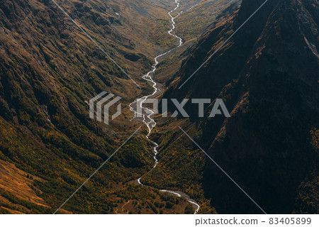 Mountain autumn landscape of the gorge. Scenic view of the river flowing in a mountain gorge, view from a height. Mountain river in the Caucasus. A gorge with a mountain river. Copy space Mountain autumn landscape of the gorge. Scenic view of the river flowing in a mountain gorge, view from a height. Mountain river in the Caucasus. A gorge with a mountain river. Copy space 83405899