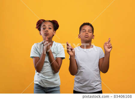 Innocent african american kids praying on yellow Innocent african american kids praying on yellow 83406108