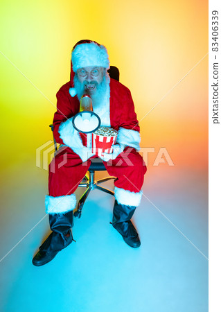 Portrait of senior man, surprised Santa Claus sitting and watching movie at cinema, indoors. Happy New Year 2022, Christmas concept Portrait of senior man, surprised Santa Claus sitting and watching movie at cinema, indoors. Happy New Year 2022, Christmas concept 83406339