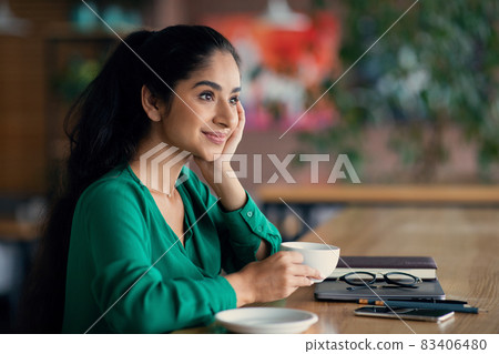 Dreamy arabic lady enjoying coffee at cozy cafe Dreamy arabic lady enjoying coffee at cozy cafe 83406480