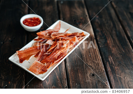 Dried chicken cut into strips on a wooden board with salt, pepper, adjiga, ketchup Dried chicken cut into strips on a wooden board with salt, pepper, adjiga, ketchup 83406957