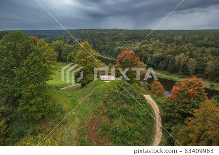 Punia mound in Lithuania with green grass and autumn trees background, road to mountain Punia mound in Lithuania with green grass and autumn trees background, road to mountain 83409963