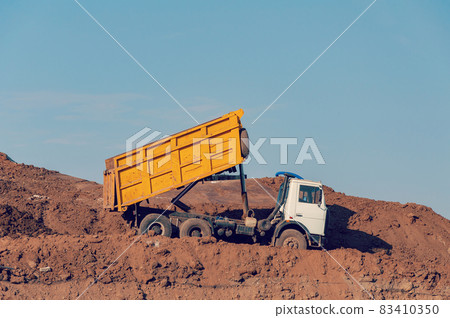 Dump truck is dumping gravel on an excavation site Dump truck is dumping gravel on an excavation site 83410350