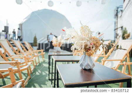 On the table is a decorative vase with dried flowers. Beautiful summer location for relaxation 83410712