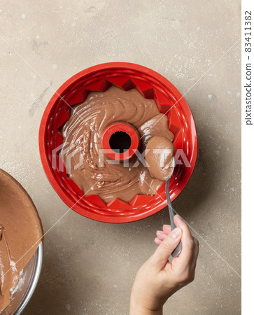putting chocolate cake dough in silicone baking form 83411382