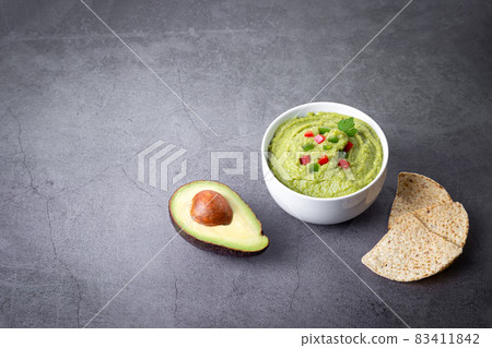 Bowl of guacamole and nachos isolated on dark background. 83411842