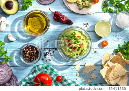 Bowl of guacamole and ingredients on blue background. Top view. Bowl of guacamole and ingredients on blue background. Top view. 83411860