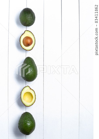 Avocados isolated on a white wooden background. Top view. Vertical format with copyspace. 83411862
