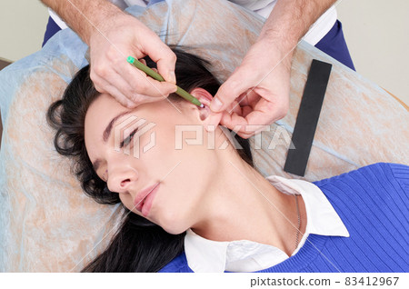 Plastic surgeon examines ear of patient before plastic surgery 83412967
