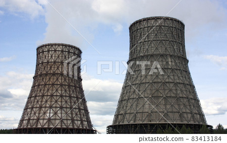 Thermal power station, cogeneration plant, two cooling towers from which smoke comes. Blue sky with clouds 83413184