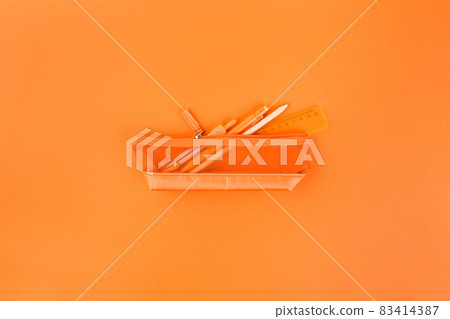 Different orange school supplies in case on orange table. Back to school concept. Flat lay, top view 83414387