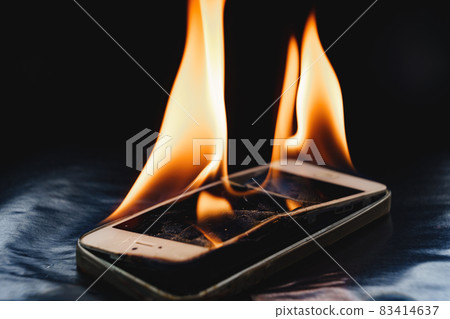 burning broken smartphone on a black background.  83414637