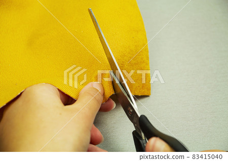 Closeup of fashion designer's hands cutting cloth with scissors in workshop. Closeup of fashion designer's hands cutting cloth with scissors in workshop. 83415040