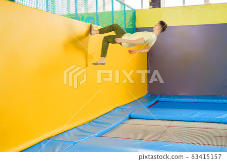 Teenage boy jumping on trampoline park in sport center Teenage boy jumping on trampoline park in sport center 83415157