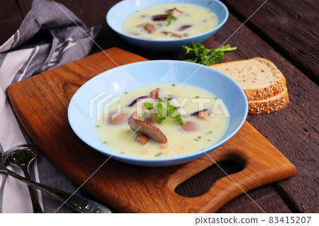 Creamy soup with boletus mushroom and herbs on wooden table 83415207